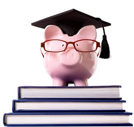 A porcelain piggy in red glasses and a college hat on it standing on the stack of blue books. White background.